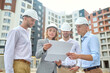 © zinkevych - Woman and men looking at drawing at construction site