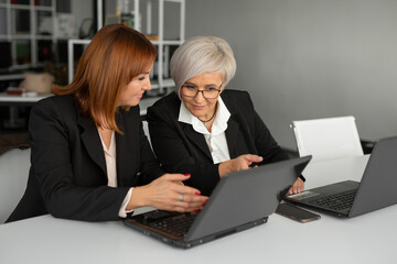 two stylish businesswoman in black suits at the workplace	
