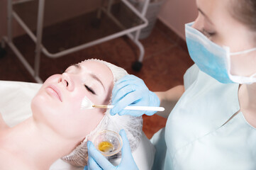 Wall Mural - face of a young woman close-up lying down cosmetic procedure is performed applying a rejuvenating mask.