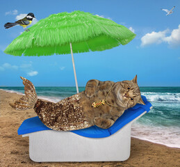 Wall Mural - A beige cat mermaid with a golden fish tail lies on a sun lounger under a umbrella by the sea.