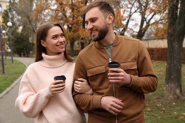 Poster - Happy couple wearing stylish clothes with cups of coffee in autumn park