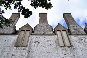 Three Chimneys & Two Windows on Stone Wall of Old House seen from Below 