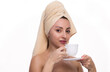 © oleg_ermak - Happy young woman with towel on her head holds cup of coffee or tea in her hand and smiles on white background. Morning routine, nice time spent