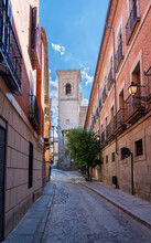 View Of Small Narrow Streets Of Toledo Spain With Clear Skies Leading To A Church