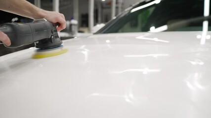 Wall Mural - The foreman on the palletizer cleans the machine. Car detailing - Car care service. Man holding a polisher in his hand. Car polishing process.