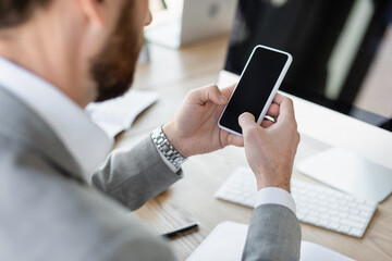 Poster - Cropped view of businessman using smartphone with blank screen in office.