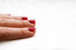 Red chipped nail polish on woman's fingernails holding pencil in office