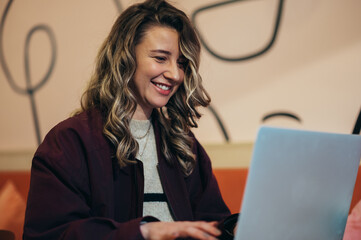 Beautiful young woman drinking coffee and working on her laptop in a cafe