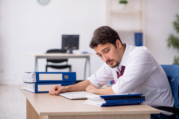 Young male employee unhappy with excessive work in the office