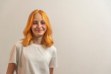 Wall Mural - portrait of a teenage girl with red hair in a white T-shirt on a light background