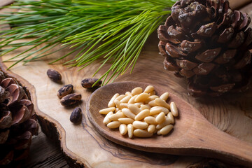 Wall Mural - Pine nuts in the spoon and pine nut cone on the wooden table. Organic food.