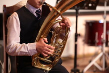 Young Man Playing A Tuba On A Golden Big Trumpet Sitting On A Chair Blowing A Mouthpiece Holding Hand Equipment Musician Frontal Close-up Portrait