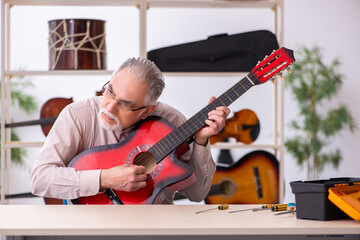 Wall Mural - Old male repairman repairing musical instruments at workplace