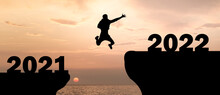 Silhouette Of Man Jump To New Year 2022 At Sunset With See Landscape, Happy New Year 2022 And Travel Adventure Concept	