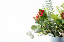A View Of A Beautiful Christmas Style Flower Bouquet, Featuring Hypericum Berries And Eucalyptus Leaves, Against A White Background.