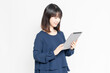 © garage38 - 白い背景の前に立って、タブレット端末を使う若い女性