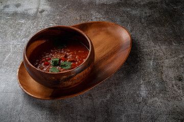 Sticker - Meat stew with parsley greens in a wooden bowl on a tray with bread crumbs against a gray stone table