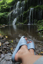 Person Sitting Alone In The Waterfall With Relax Feet. Self Love Care And Healing Moment Concept. Relaxation With Nature. 