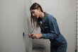 © kalinichenkod - a beautiful young woman makes repairs at home
