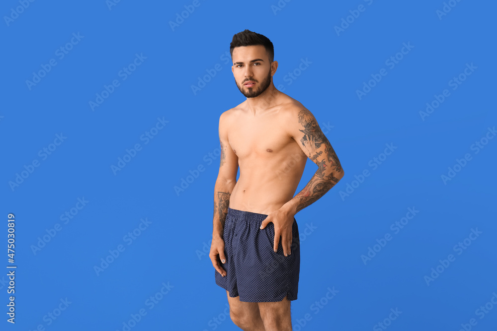 Handsome young man in underwear on color background