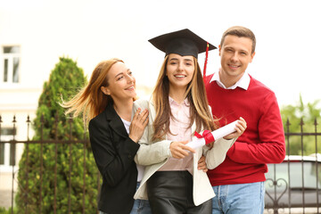 Wall Mural - Happy young woman with her parents on graduation day