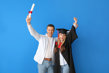 Wall Mural - Happy female graduation student with her father on color background