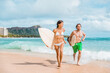 © Maridav - Hawaii surfing couple surfers in Waikiki beach, Honolulu Asian girl and Caucasian guy surfer carrying surfboards running out of water. Surf lifestyle Oahu island. USA travel. Fun vacation activity.