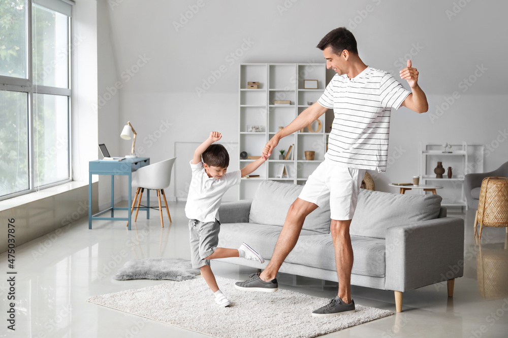 Man and his little son dancing at home