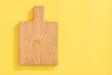 Poster - Handmade cherry wood wooden cutting board on orange yellow background.