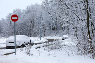 Wall Mural - Cars covered with snow on winter road near the forest and stop sign. Weather after snowfall