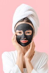 Wall Mural - Young woman with activated charcoal mask on her face against color background