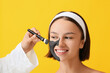 © Pixel-Shot - Cosmetologist applying activated charcoal mask on woman's face against color background