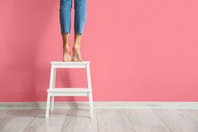 Woman Standing On White Stepladder Near Pink Wall