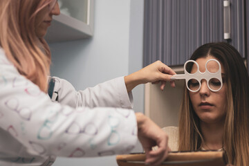 A girl undergoes an accommodation flexibility test using flippers at an optician.