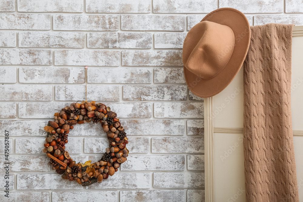 Beautiful acorn wreath on light brick wall and clothes in room