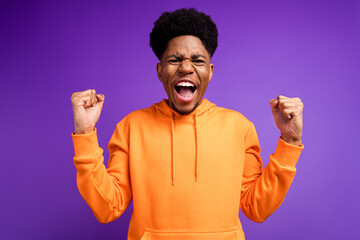 Wall Mural - Photo of cheerful young dark skin man winner good mood celebrate champion fists isolated on purple color background