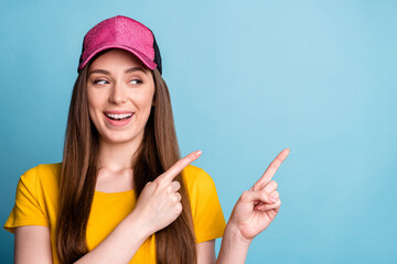 Sticker - Photo of curious lady indicate forefingers empty space look side wear pink cap yellow t-shirt isolated blue color background