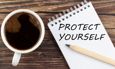 PROTECT YOURSELF text on notebook with coffee on the wooden background