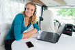 woman inside campervan smiling using laptop