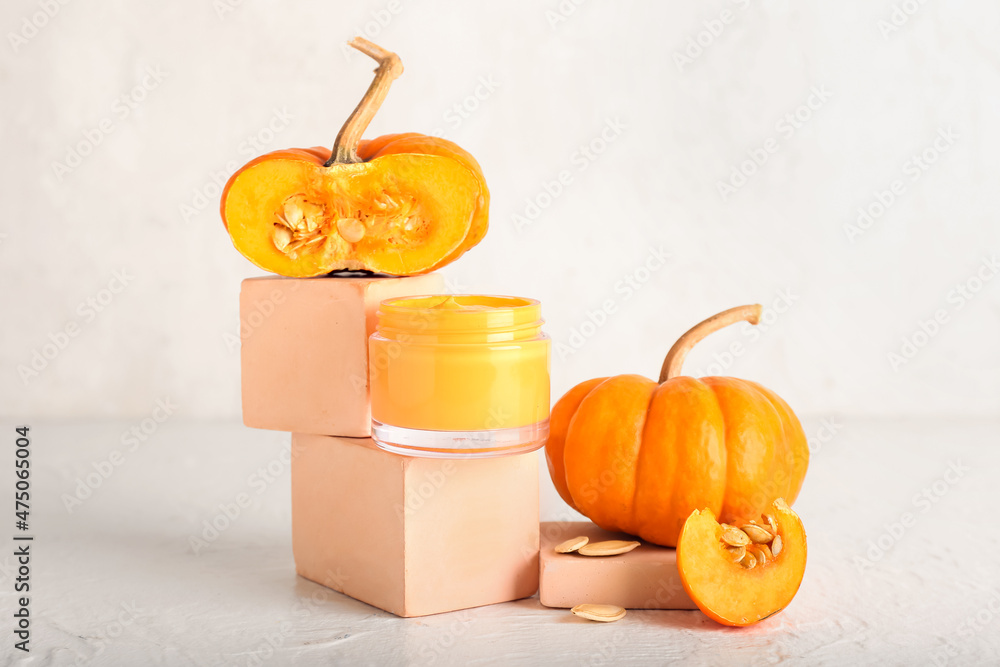 Composition with jar of natural mask and pumpkins on light background