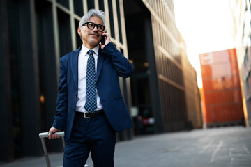 Wall Mural - Senior businessman outdoors. Middle-aged businessman talking to the phone..