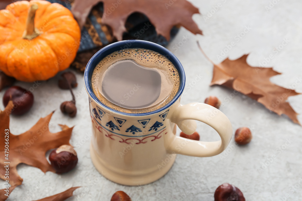 Cup of delicious pumpkin coffee on light background