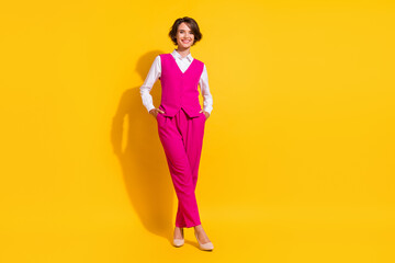 Sticker - Full length body size view of attractive cheerful businesswoman holding hands in pockets isolated over bright yellow color background