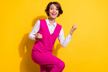 Poster - Photo of pretty lucky young woman dressed pink suit rising fists empty space smiling isolated yellow color background