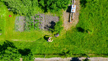 Aerial View Of Farmer Mowing A Lawn In His Garden With A Petrol Lawn Mower