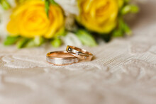 Two Wedding Rings On A Background From Yellow Roses