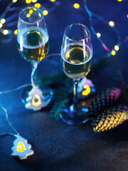 Sticker - Two glasses of champagne, a Christmas composition. Blue background with a garland in the shape of a Christmas tree