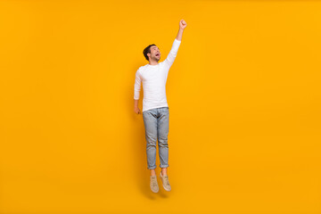 Wall Mural - Full size photo of impressed brunet millennial guy jump wear shirt jeans sneakers isolated on yellow background