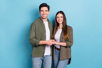 Poster - Photo of sweet charming young lady guy wear green shirts holding arms smiling isolated blue color background