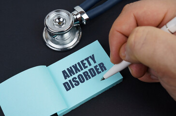 On a black table is a stethoscope and a notebook in which the man wrote - ANXIETY DISORDER